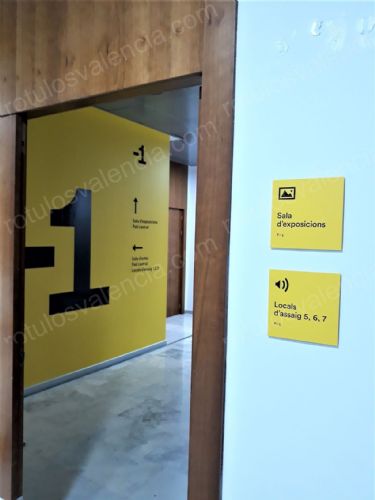 Detalle de pared revestida en amarillo para el Centro Cultural Matilde Salvador y placas de señalización